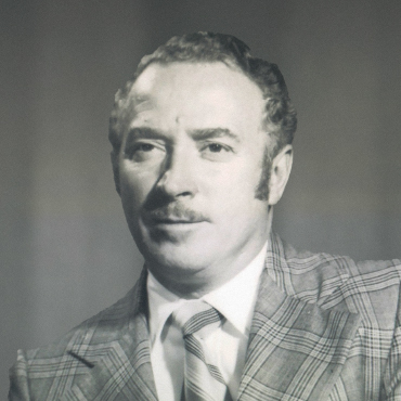 Black and white portrait of Albert Roberts wearing a plaid suit jacket, dress shirt, and tie, looking slightly to the side with a neutral expression.