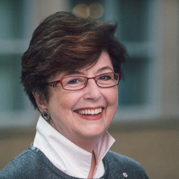 A colorful portrait of Susan Dyer Knight. She is wearing a light green sweater, with white shirt underneath. She is smiling.