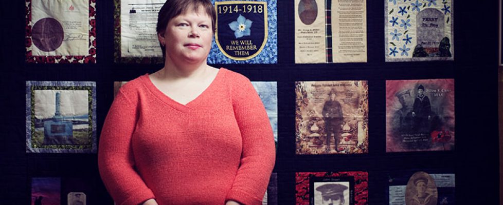 Tracy Madore in front of Peace-by-Piece: Quilted Memories of Newfoundland in the Great War