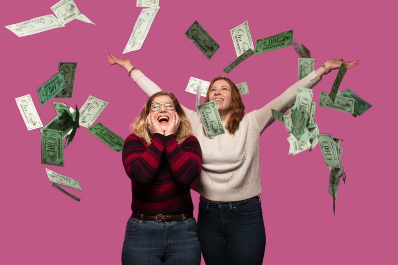 Two humanities and social sciences students throwing fake money up into the air