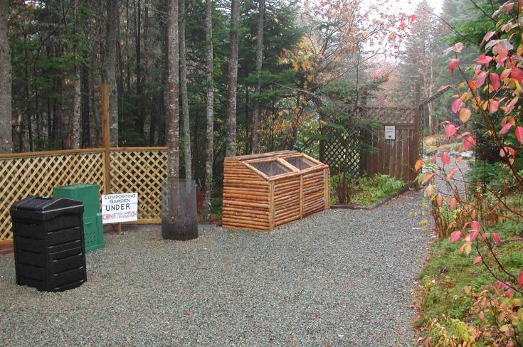 Compost area featuring several compost bins before the pollinator garden