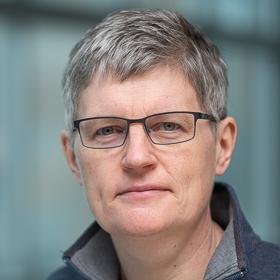 A headshot-style photograph of Jeannette Byrne. She is seen from the mid-chest up and is looking at the camera
