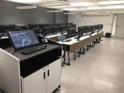photo of classroom taken showing a lectern and rows of tables and seats