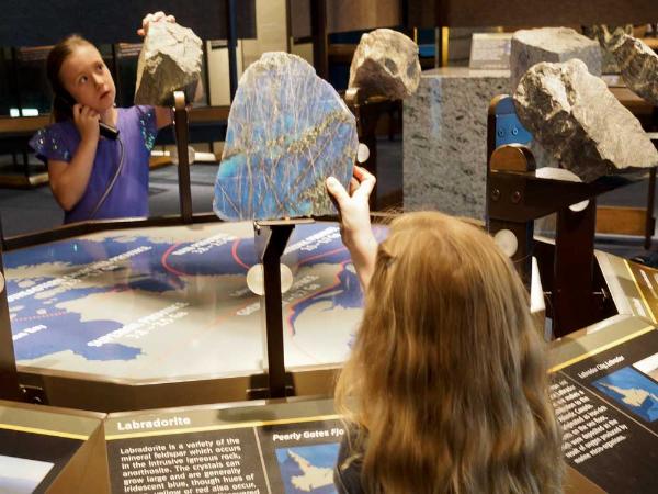 two children examine rock displays including a large piece of Labradorite