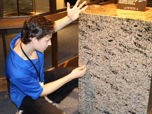 an interpreter examines a column of polished rock