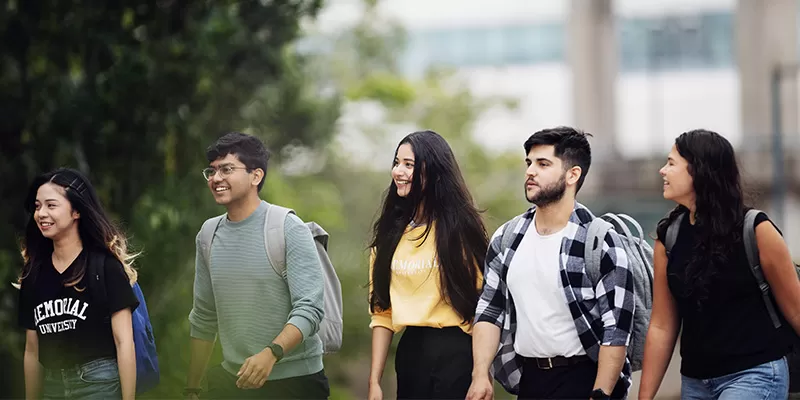 Five students with backpacks walking outside