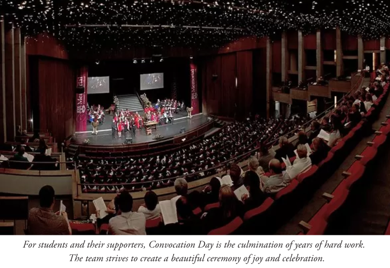 People in gowns on stage with a full audience.