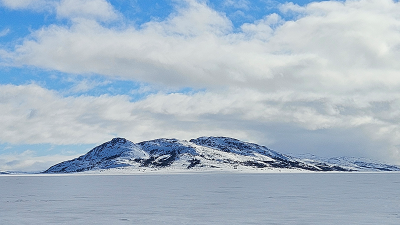 A snow topped mountain in the middle of the ocean