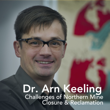 A man with dark brown hair and black glasses, with the words "Dr. Arn Keeling" written on top of his dark collared shirt