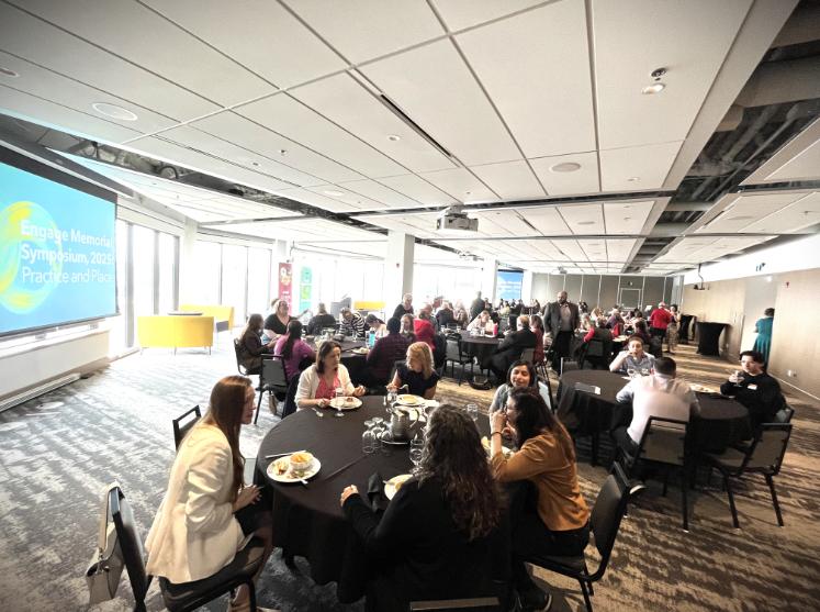 Conference attendees sit at big, round tables having conversations.